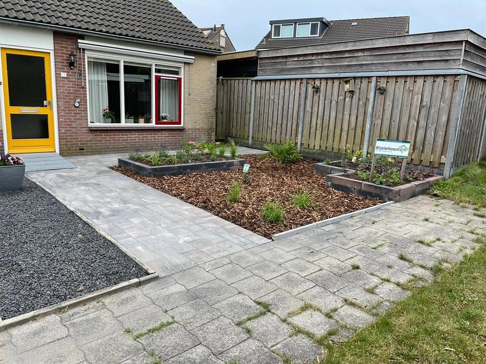Voortuin met nieuwe borders, sierbestrating en een houten schutting