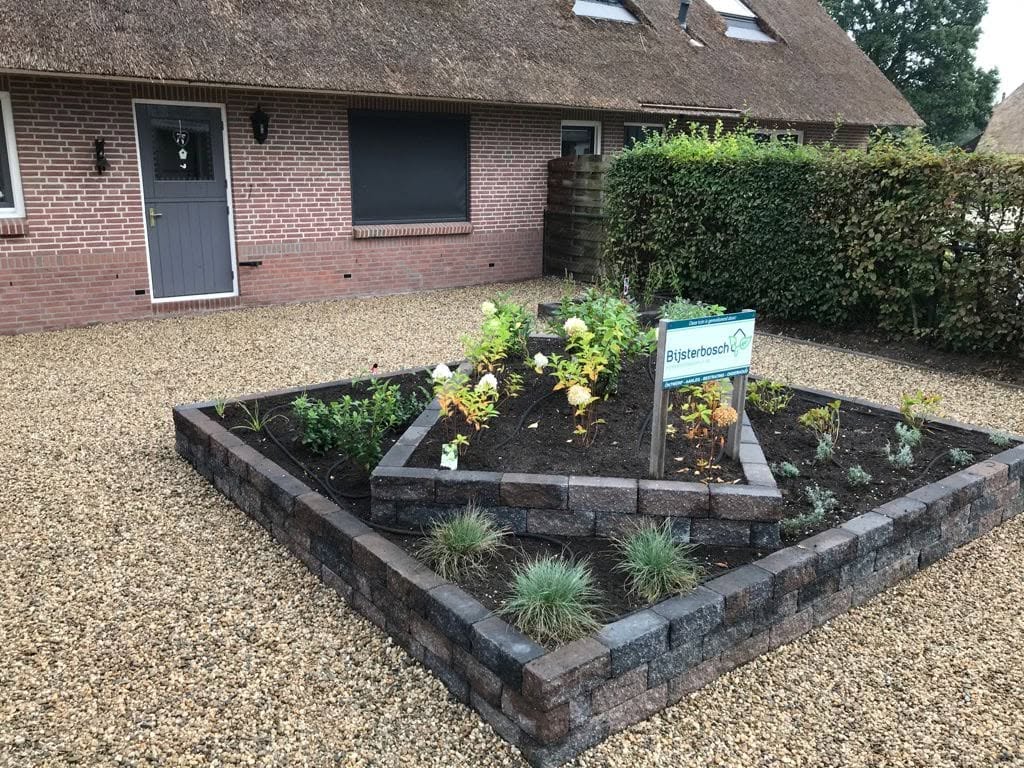 Voortuin met nieuw beplante borders en een bord van Bijsterbosch Hoveniersbedrijf