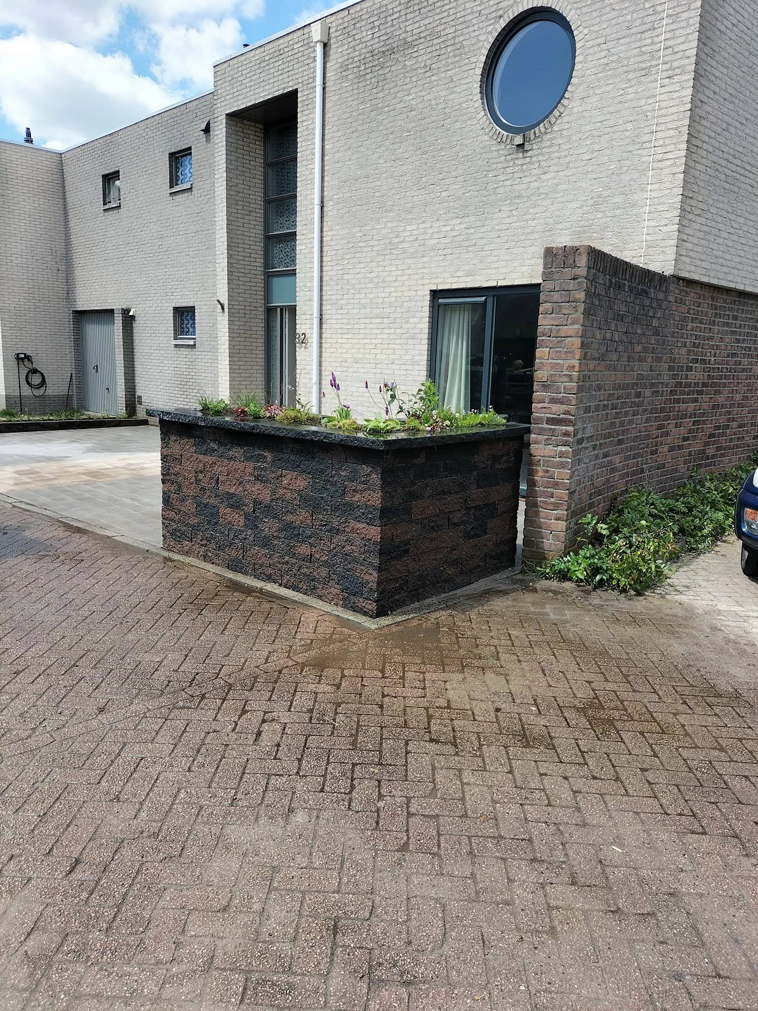 Gemetselde plantenbak met beplanting bij de entree van een woning