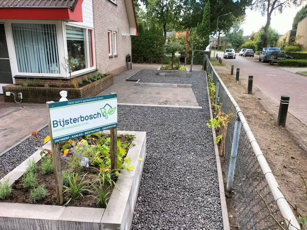 Voortuin met grind, bestrating en een bord van Bijsterbosch Hoveniersbedrijf aan de straat