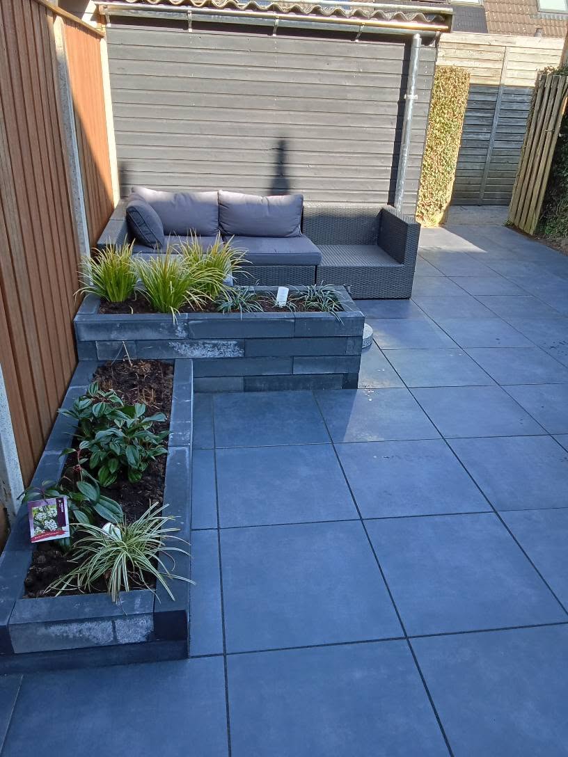 Terras met loungeset en plantenbakken naast een woning