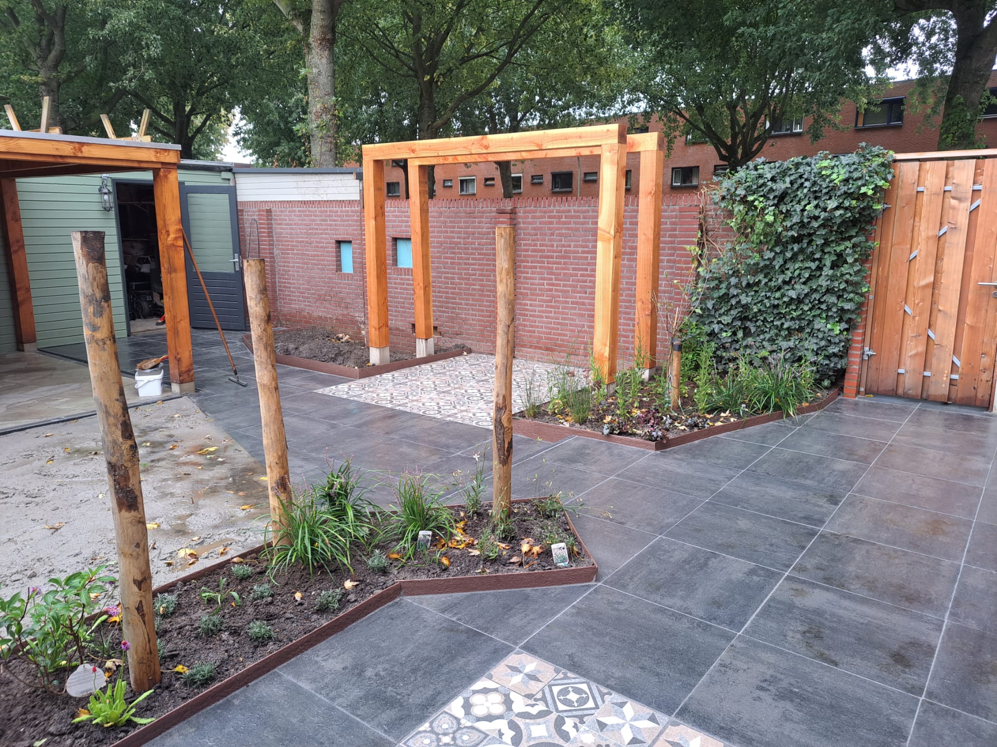 Houten pergola boven nieuwe bestrating in een tuin