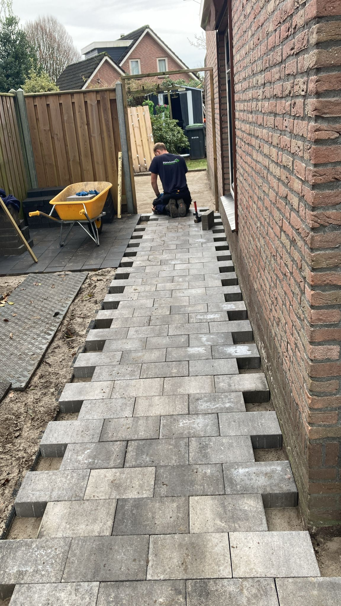 Klinkers worden gelegd voor een pad langs een woning